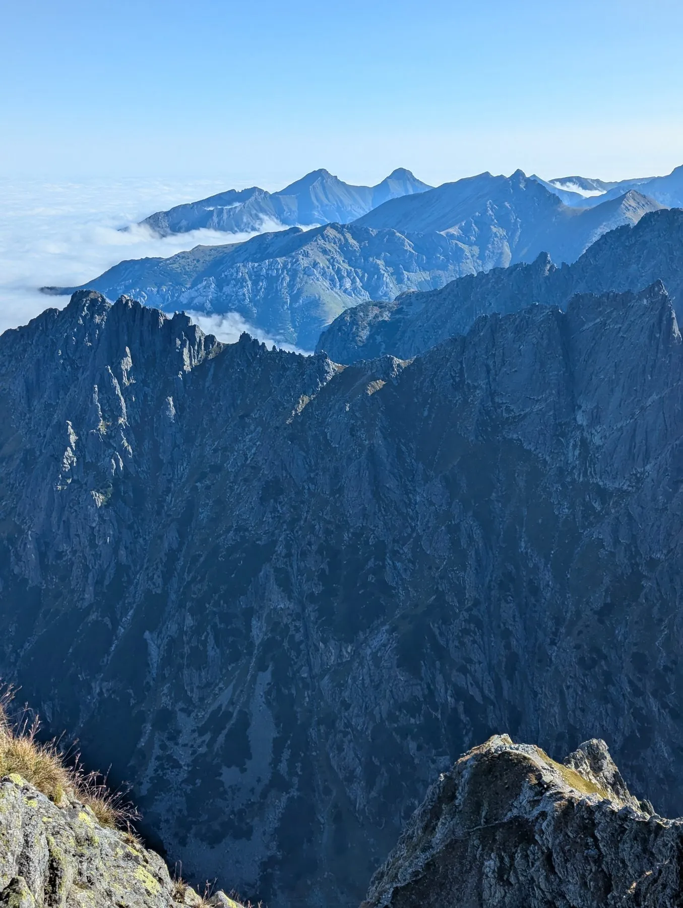 Skalne ściany po drugiej stronie doliny, w tle szczyty nad chmurami